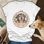 A white V-neck t-shirt featuring an embroidered hoop graphic with a black dog and the text Silver and Sweet.
