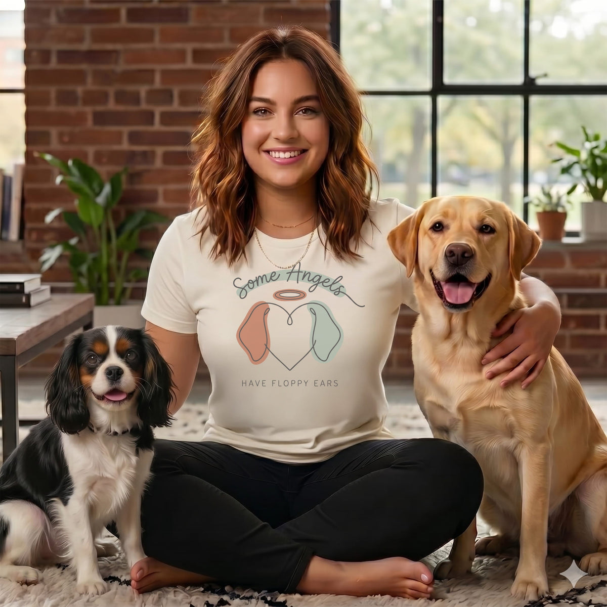 Woman wearing a t-shirt with "Some Angels Have Floppy Ears" and holding two dogs.