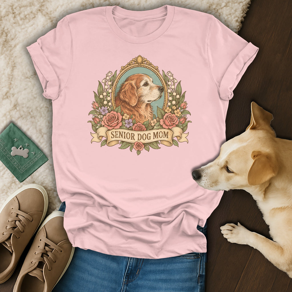 A light pink t-shirt featuring a vintage-style graphic of a golden dog surrounded by flowers and the text "Senior Dog Mom."
