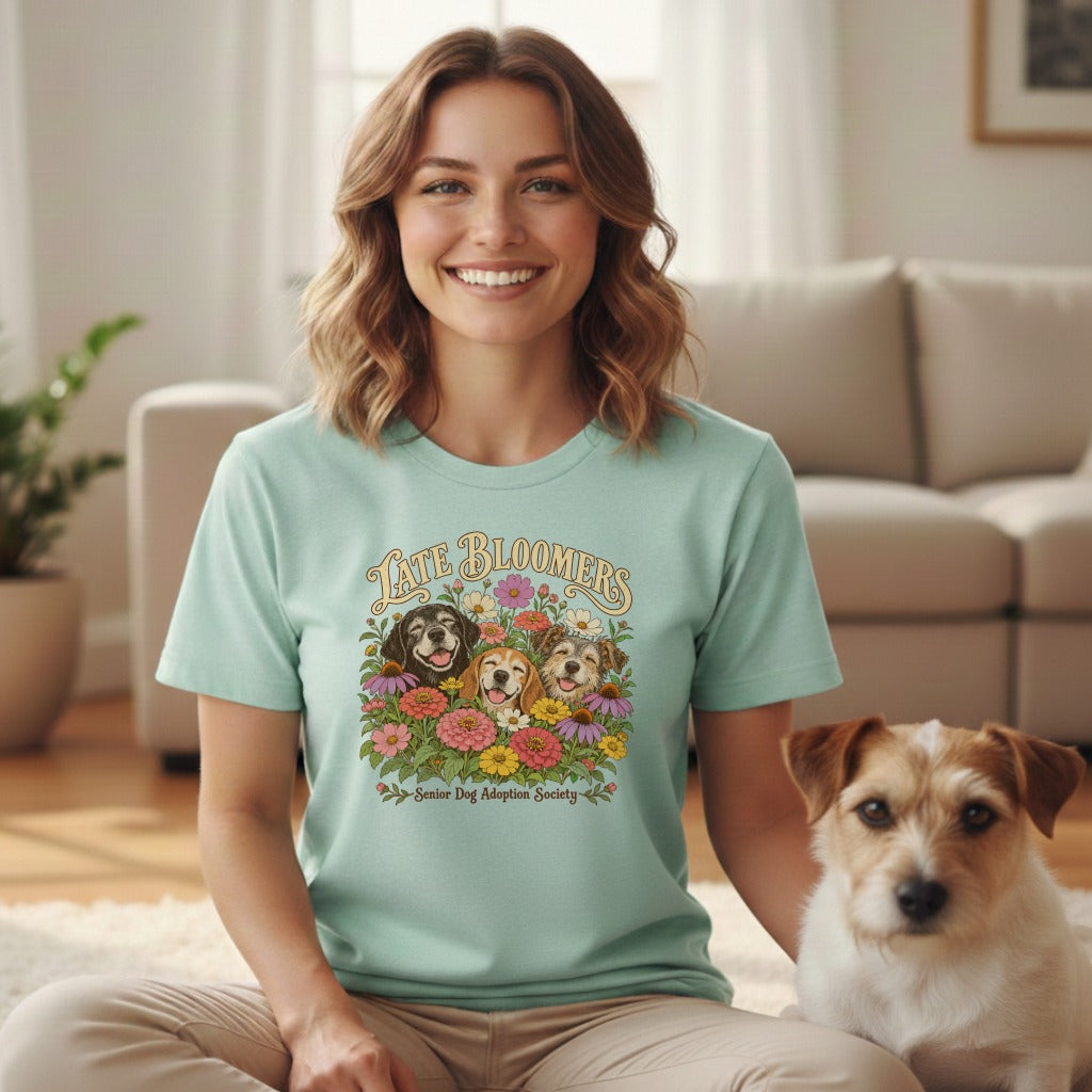 A smiling woman wearing a mint-green t-shirt featuring a dog graphic, sitting next to a terrier.