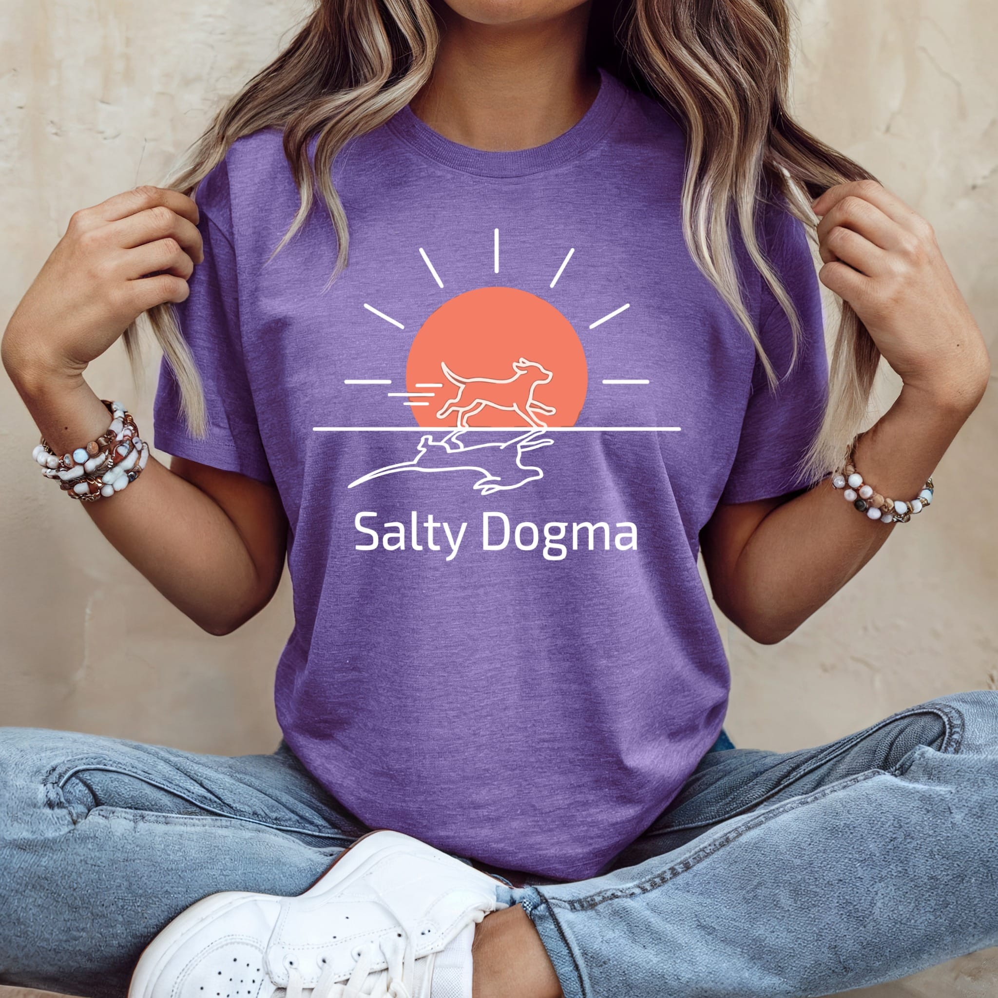 Purple t-shirt with a white line drawing of a dog running towards a sun.