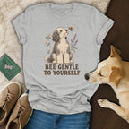 A gray t-shirt featuring a doodle dog illustration and the text "BEE GENTLE TO YOURSELF".