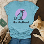 Blue t-shirt with a dog silhouette wearing pink sunglasses and the text "One of a Hound".