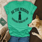 Green t-shirt with a black dog silhouette and text "BE THE PERSON YOUR DOG THINKS YOU ARE".
