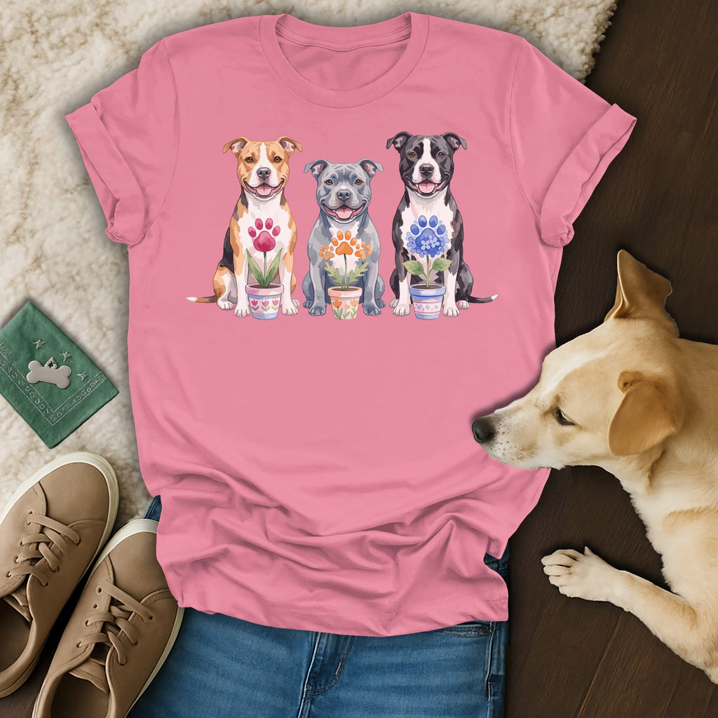 Three watercolor pit bulls sitting and holding potted flowers on a pink t-shirt.