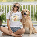 Woman in white t-shirt with dogs and "Born Free Born Fluffy" text, sitting with golden retriever.