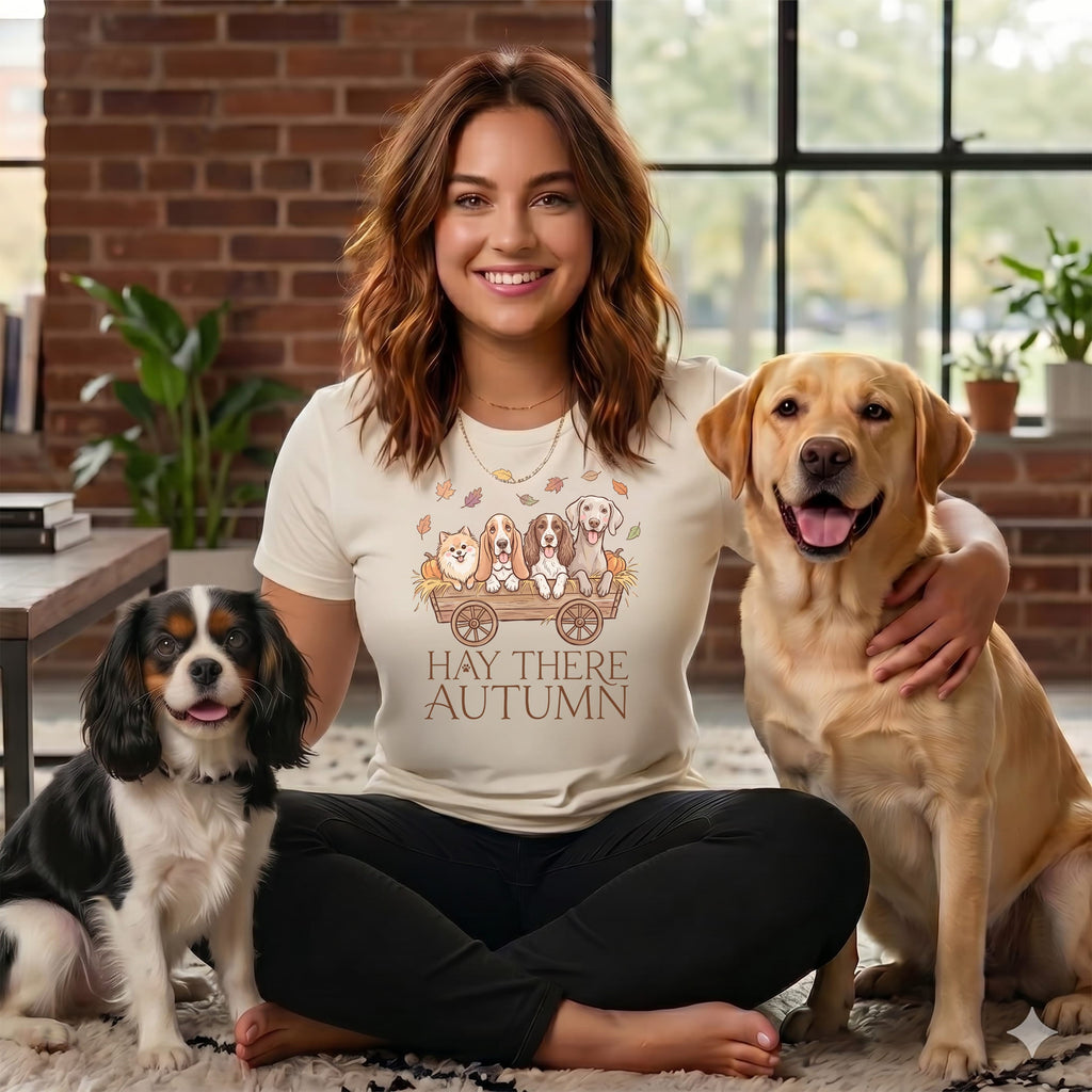 Woman in shirt with dogs and "Hay There Autumn" text, with two dogs beside her.