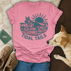 Pink t-shirt with a German Shepherd surfing on waves at sunset, "TIDAL TAILS" text.