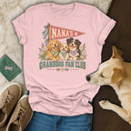A light pink t-shirt featuring a graphic of three dogs and text reading Nana's Granddog Fan Club.