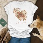 White t-shirt with heart graphic of dog, flowers, leaves, acorns, and mushrooms. Text says "fall in love".