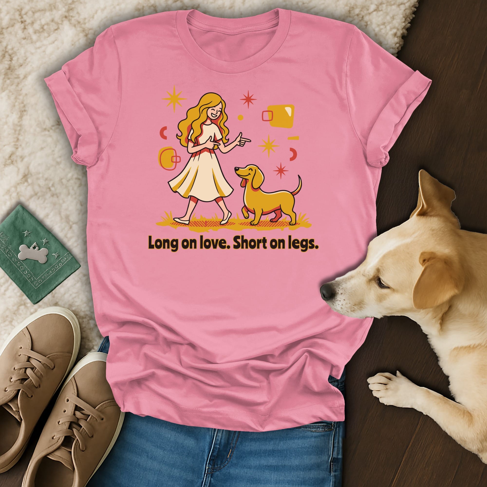 Pink t-shirt with graphic of a blonde woman and yellow dog with text "Long on love. Short on legs."