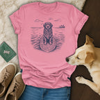 Pink t-shirt with a black line drawing of a dog on a surfboard.