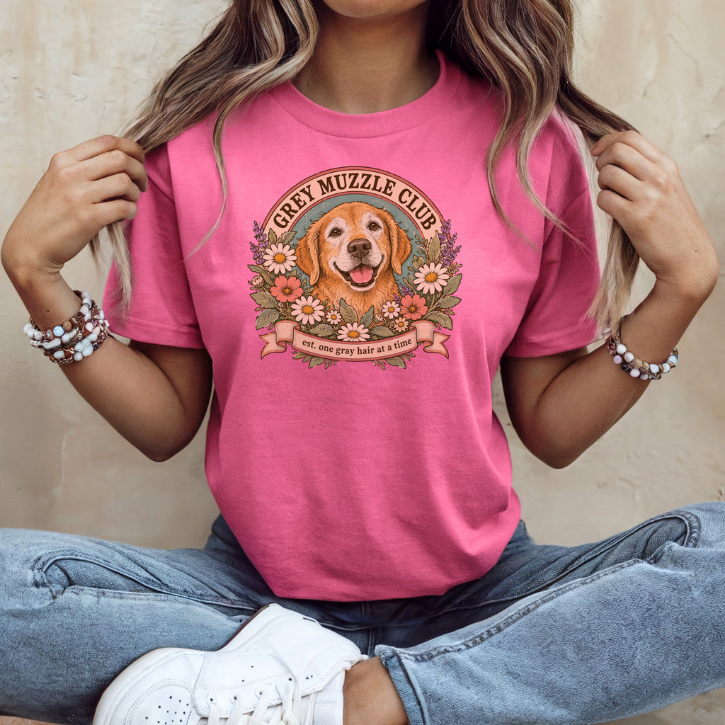 A woman wearing a pink t-shirt with a vintage graphic of a golden retriever and flowers.