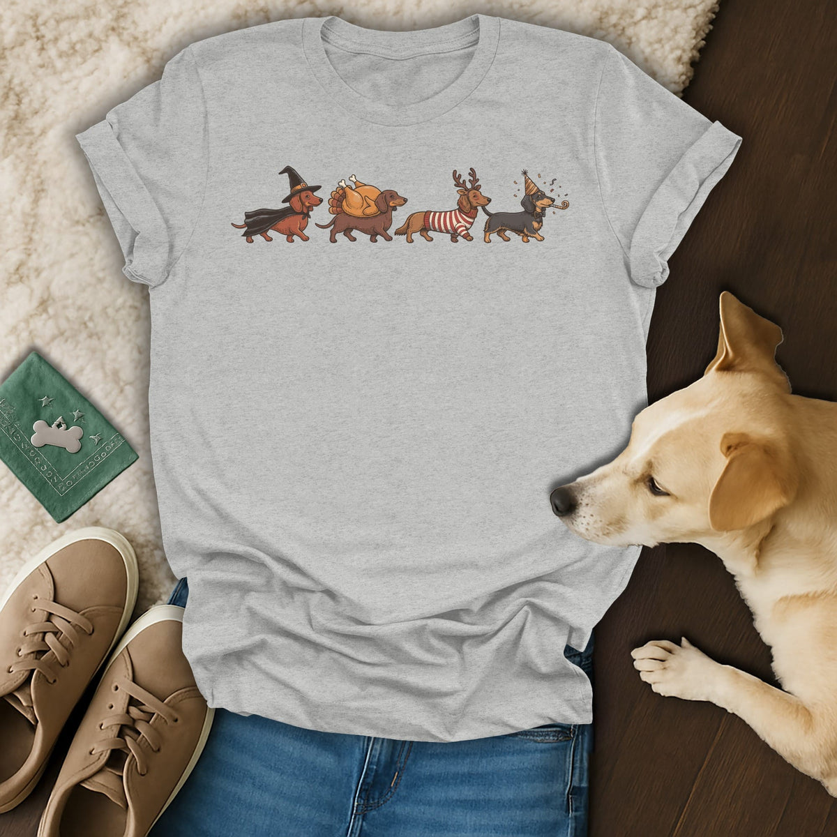 Grey t-shirt with graphic of four dachshunds in holiday costumes: witch, turkey, reindeer, and party hat.