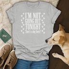 Grey t-shirt with white text "I'M NOT GOING OUT TONIGHT There's a dog there?" and paw prints.