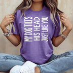 Purple t-shirt with white text reading "My dog tilts his head just like you".