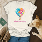 White t-shirt with colorful hot air balloon and paw print, dog resting beside it.