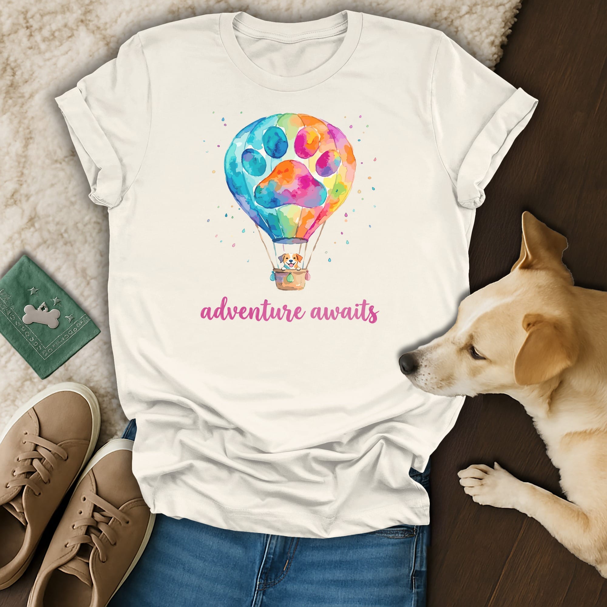 White t-shirt with colorful hot air balloon and paw print, dog resting beside it.