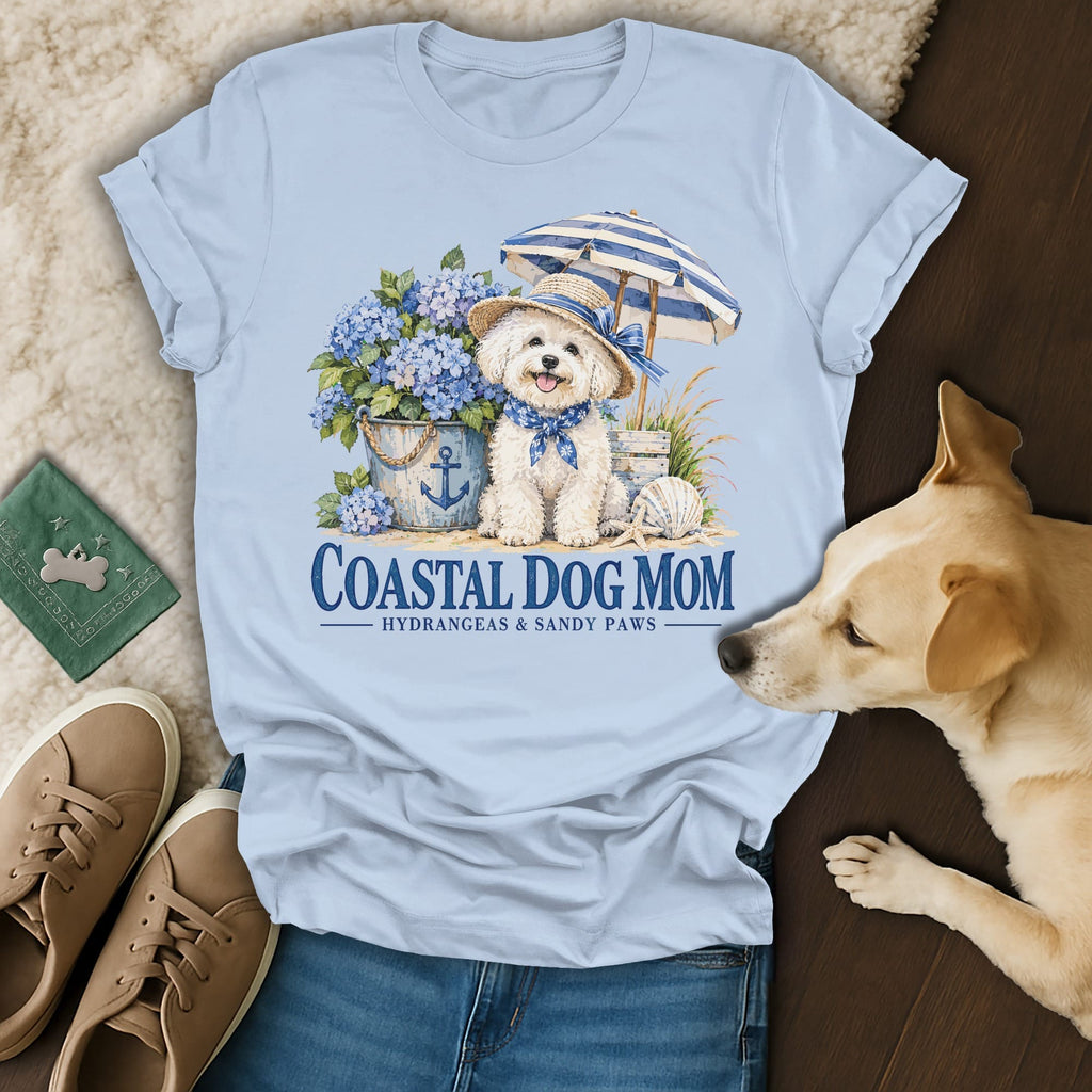 Light blue t-shirt featuring a graphic of a white dog wearing a hat, surrounded by hydrangeas and beach items.