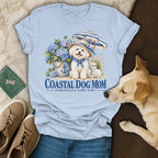 Light blue t-shirt featuring a graphic of a white dog wearing a hat, surrounded by hydrangeas and beach items.