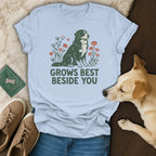 Light blue t-shirt featuring a graphic of a dog surrounded by flowers and the text GROWS BEST BESIDE YOU.