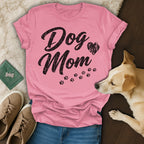 Pink t-shirt with "Dog Mom" text and paw prints, laid flat with a dog.