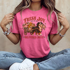 A person wearing a pink t-shirt with a graphic of a Bernese Mountain Dog pulling a flower-filled cart, accompanied by the text "Fresh Joy Delivered Daily."