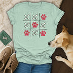 Light blue t-shirt with a tic-tac-toe grid featuring paw prints and bones.