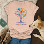 T-shirt with a colorful paw print tree and "rooted in love" text.