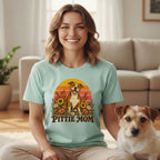 A smiling woman wears a mint green t-shirt with a graphic of a pit bull and sunflowers, featuring the text Pittie Mom.