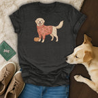 Golden retriever in a pumpkin sweater next to a pumpkin on a dark t-shirt.