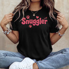 Black t-shirt with pink "Snuggler" text and paw prints.