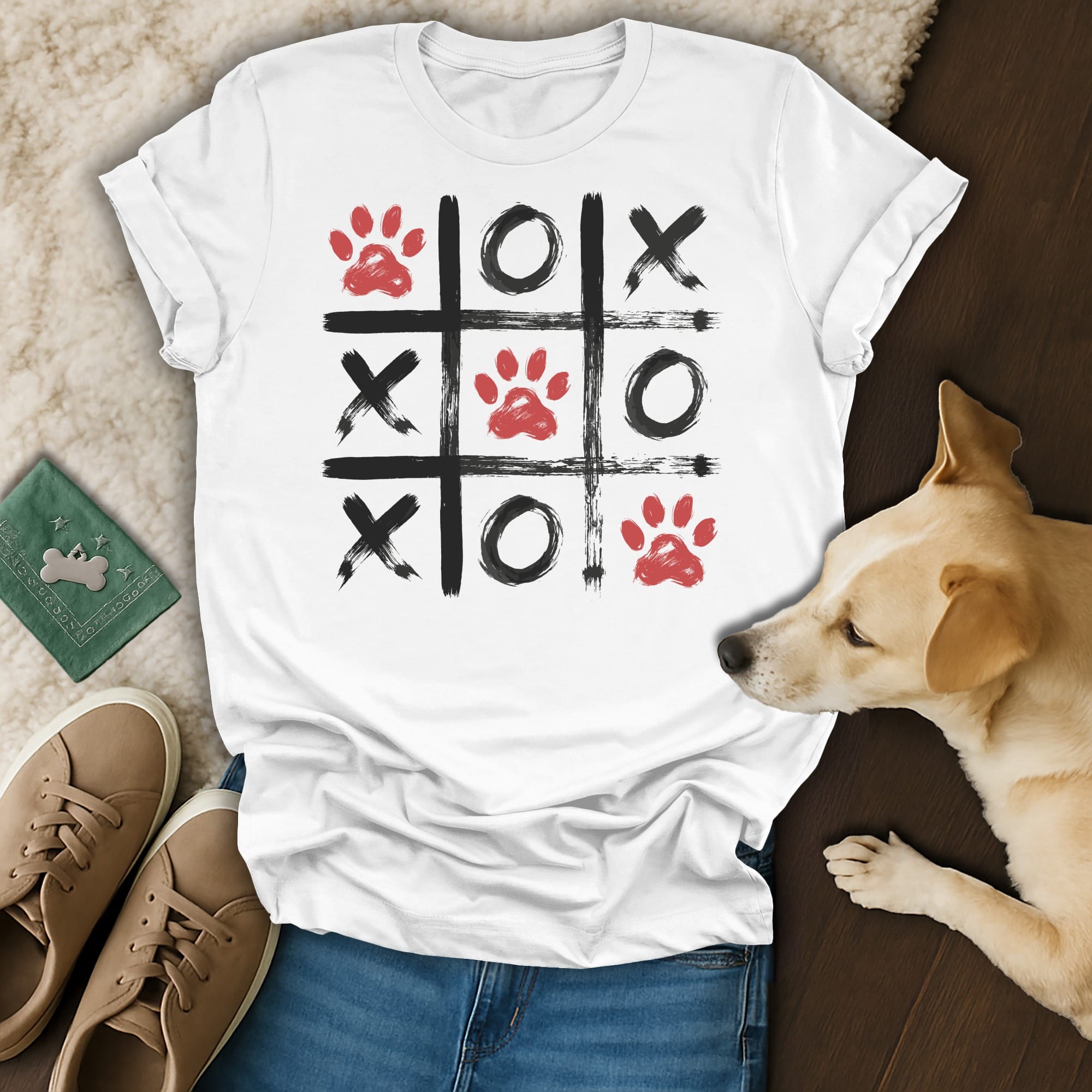 White t-shirt with a tic-tac-toe grid design featuring red paw prints.