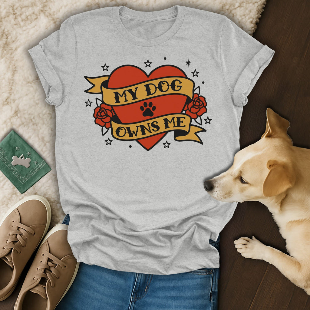 Gray t-shirt with "MY DOG OWNS ME" text inside a heart, on a flat lay.