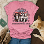 Pink t-shirt with three huskies and text "STILL BEGGING FOR TABLE SCRAPS".