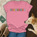Pink t-shirt with a paw print patchwork design, displayed with jeans, sneakers, and a dog.