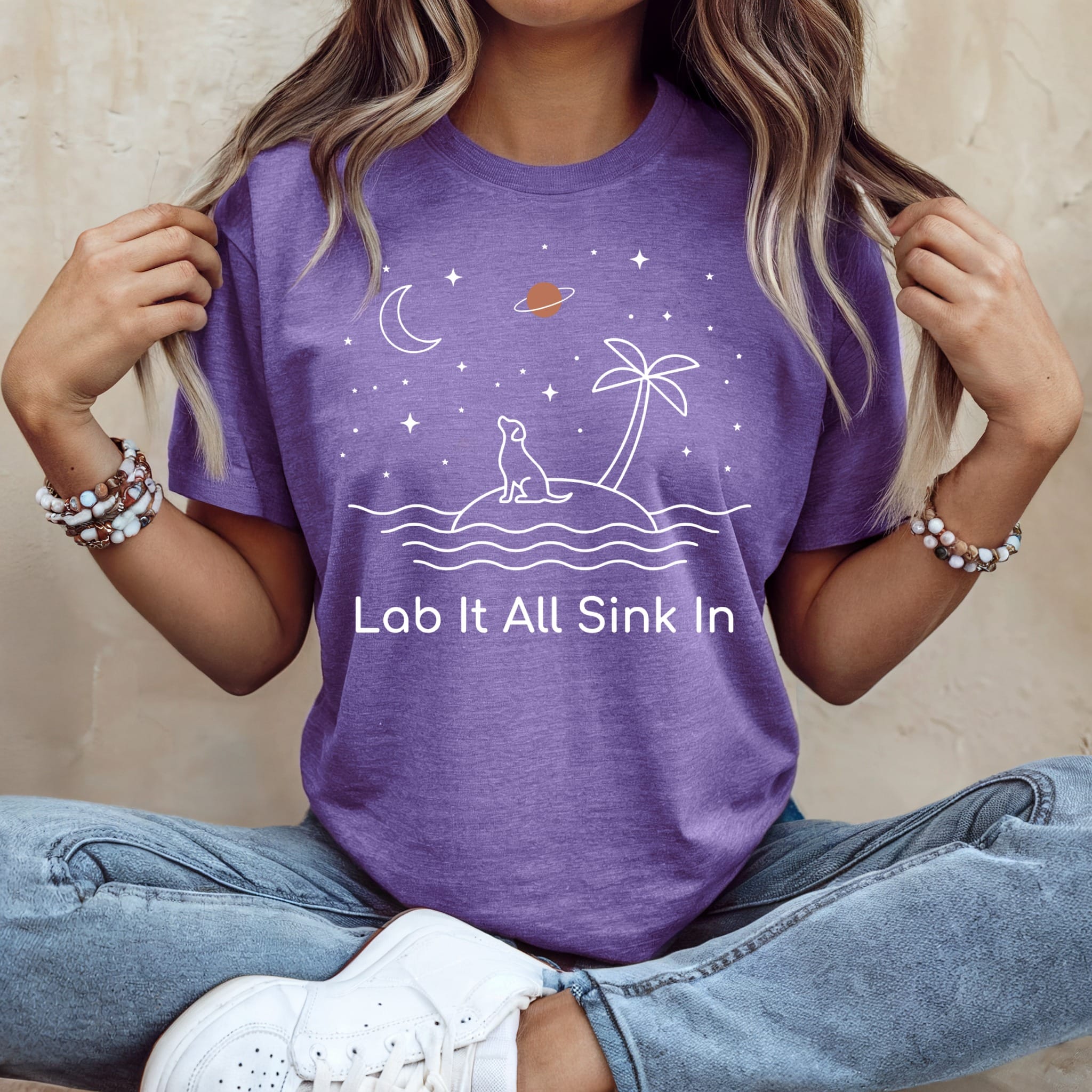Purple t-shirt with a dog on an island, moon, stars, palm tree, and text "Lab It All Sink In".