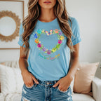 Light blue t-shirt with a heart wreath of colorful paw prints, flowers, and a butterfly. Text says "Grow Wild, Love Dogs."