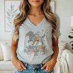 T-shirt with a retro graphic of a multi-colored dog holding a book, reading glasses, and the text "NOVEL RETRIEVER".