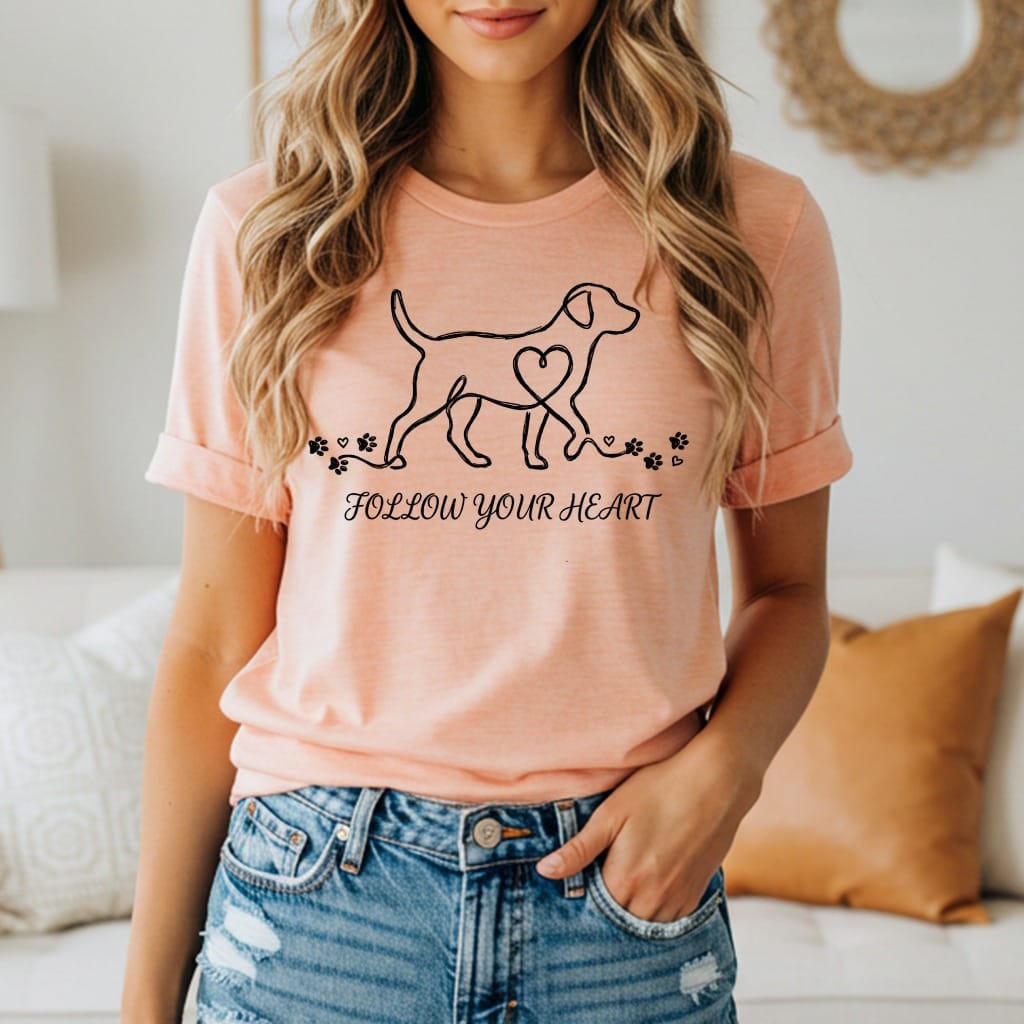 Peach t-shirt with a minimalist dog outline, heart, and paw prints. Text says "FOLLOW YOUR HEART".