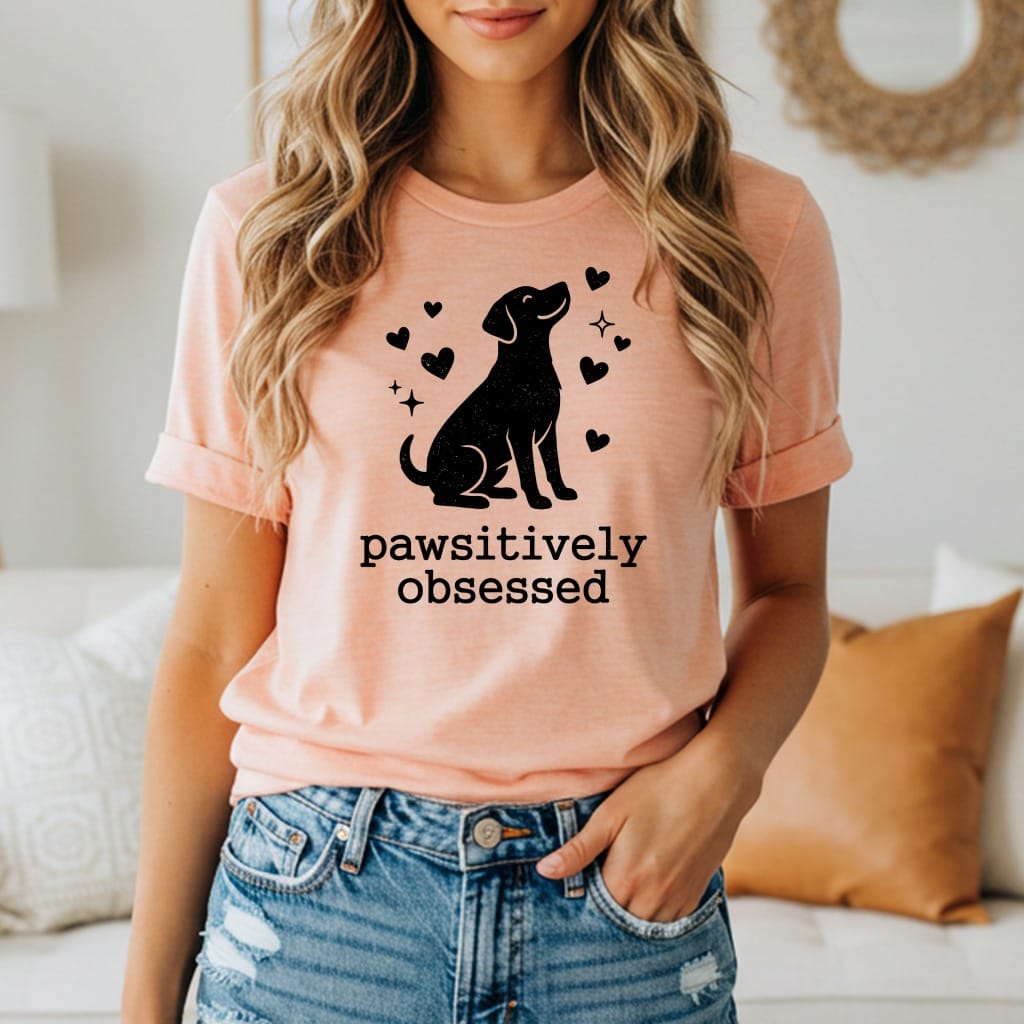 Peach t-shirt with black dog silhouette and hearts, "pawsitively obsessed" text.