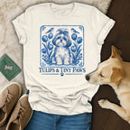 Off-white t-shirt with a blue graphic of a dog, tulips, and birds, featuring the text "Tulips & Tiny Paws".