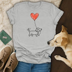 Light grey t-shirt featuring a black outline drawing of a dachshund holding a red heart balloon.