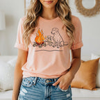 Line drawing of dogs and campfire on a peach t-shirt.