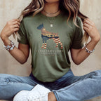 Olive green t-shirt with dog silhouette filled with US flag, text "Land That I Love".