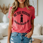 Woman wearing coral t-shirt with black dog silhouette and text.