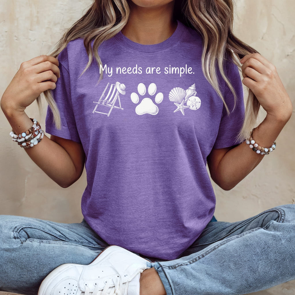 Purple t-shirt with white graphic: "My needs are simple.", paw print, beach chair, and shells.
