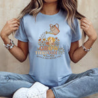Light blue t-shirt graphic with dog, flowers, and text "GROW THROUGH IT WITH A DOG BESIDE YOU".
