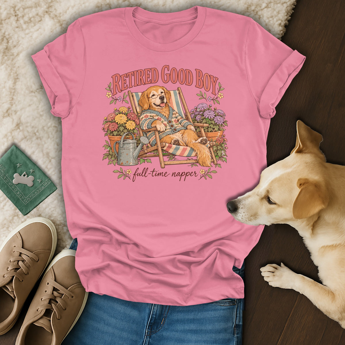 Pink t-shirt with a graphic of a golden retriever relaxing in a deck chair, surrounded by flowers.
