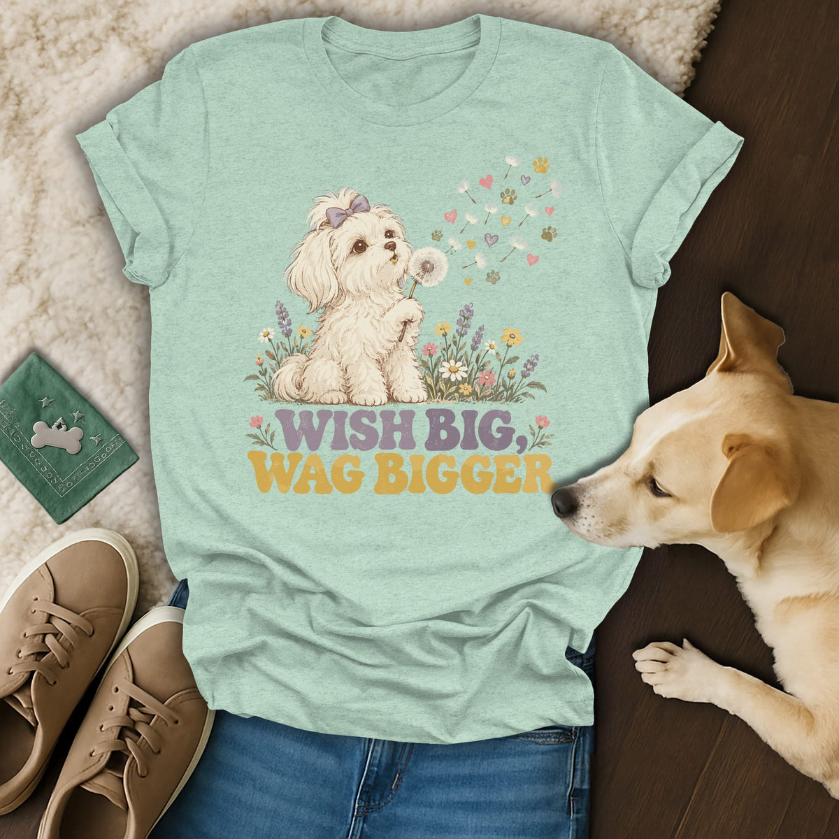 Light green t-shirt featuring a graphic of a white puppy blowing dandelion seeds with text reading WISH BIG WAG BIGGER.